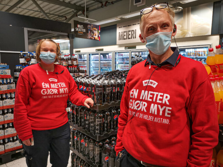 Assisterende butikksjef Veronica Kristensen (t.v.) og butikksjef John Ellingsen i Meny Kongssenteret vil sammen med de øvrige ansatte bruke munnbind i tiden fram til jul. Det er til det beste både for kunder og ansatte. For ordens skyld kan vi opplyse at de begge smiler bak munnbindene.