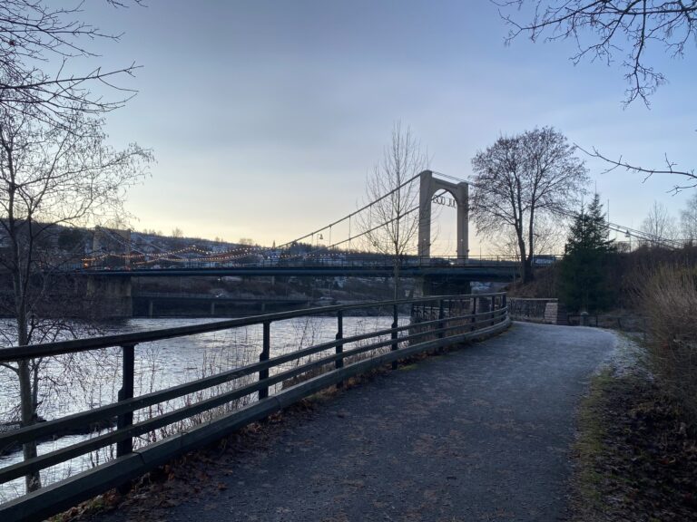 Rim i gresset og litt småglatt på asfalten langs elvepromenaden ved møllesteinene.