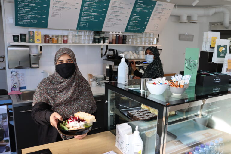 Tehseen Hussein serverer en tyrkisk salat. I bakgrunnen driver Nosheen med kaffe.