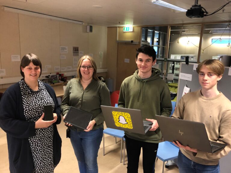 Bibliotekar Marianne Skog Eltvik (t.v.), skolebibliotekar Marte Østmoen, Moritz Myrseth og Sondre Erichsen tar imot folk som måtte trenger teknologisk hjelp på torsdager.