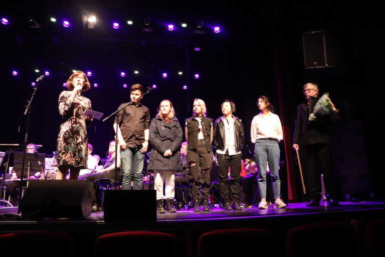 Leder for kommunens komité for miljø og samfunnsutvikling, Inger Noer, deler ut Barn og unges kulturpris for 2021 til Pride-arrangørene. Konferansier Øivind Roos ledet arrangementet der prisutdelingen inngikk: Glommasvingen Janitsjars 25-års jubileumskonsert.