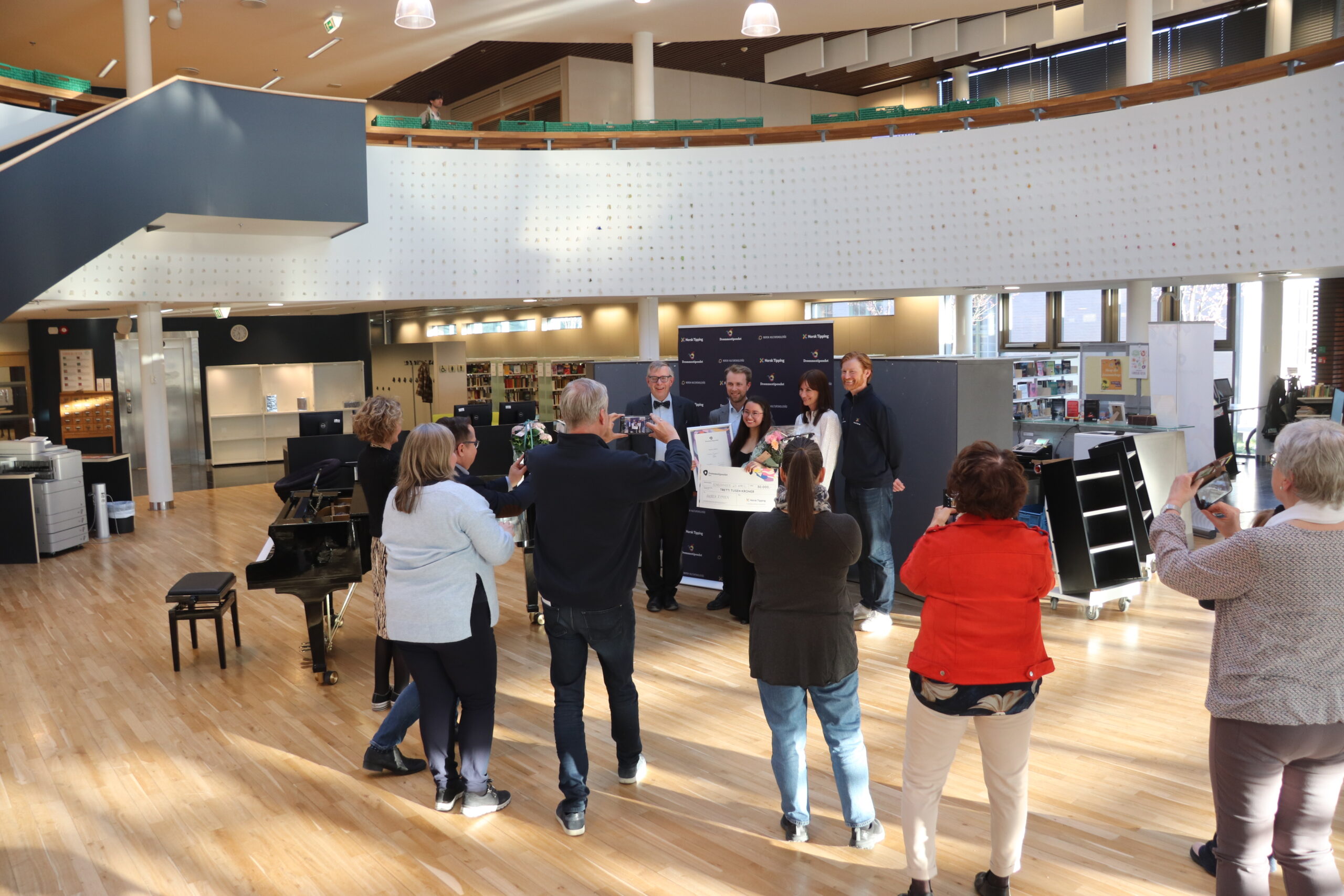 Fotografering av stipendvinner og gratulanter. Lengst bort, fra venstre, leder av Teater i Glåmdal, Øivind Roos, rådgiver Jens Nyland i Norsk Kulturskoleråd, kultursjef Stine Raaden i Kongsvinger kommune og Bernt Plassgård fra Norsk Tipping.