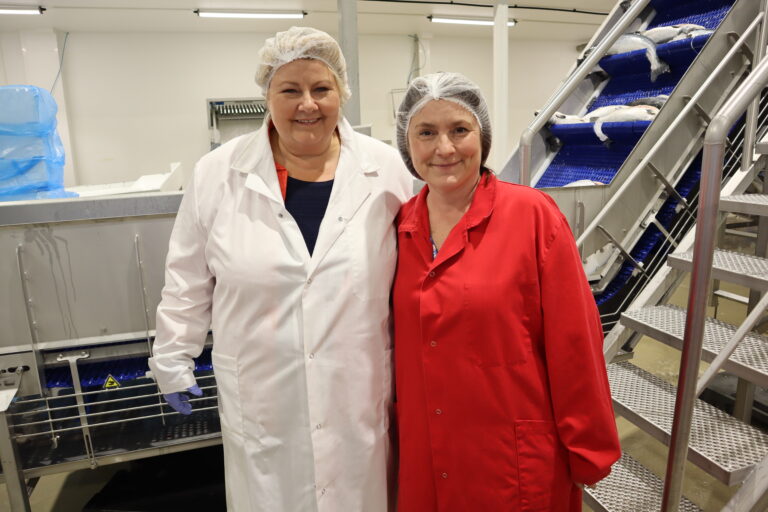 Høyre-leder Erna Solberg (t.v.) og ordfører i Kongsvinger, Eli Wathne, her i full utrustning på besøk hos laksefabrikken First Seafood AS på Siva.