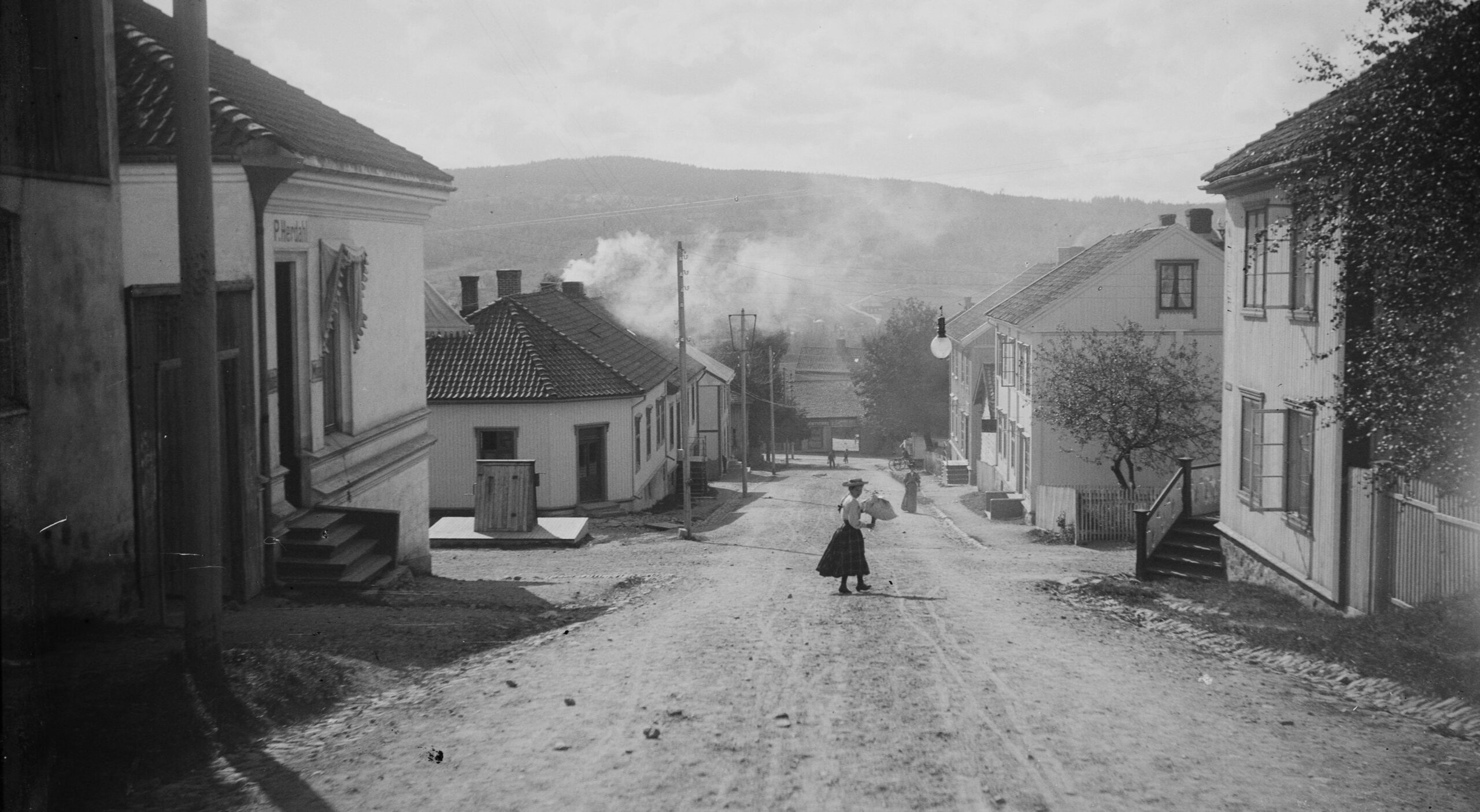 Bildet viser Storgata med Herdahlsalen til venstre. Holmengården er skjult bak et tre nederst.