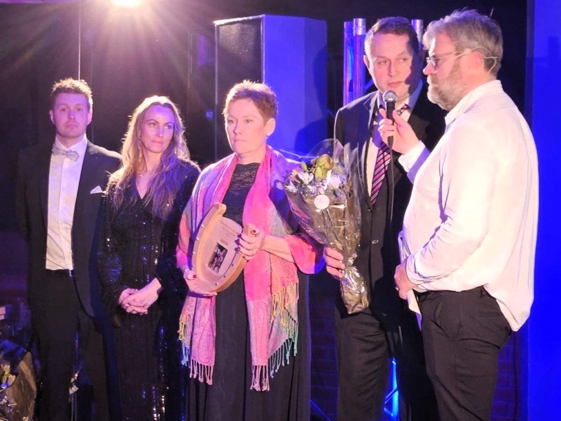 Severin og Linda Aarskog (f.h) får prisen for Innlandets beste 3-åringe varmblods, sammen med eierrepresentanter.