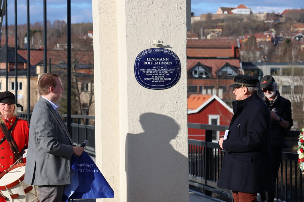 Oskar Aanmoen (t.v.) og Jon Syse avduket blått skilt for Lensmann Rolf Jahnsen på Kongsvinger bru , på dagen 84 år etter at lensmannen ble skutt av tyske soldater på samme sted.