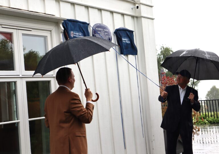 I pøsende regn skulle fire blå skilt avdukes under hedringen av Skansgården på søndag. Historiker Oskar Aanmoen (t.v) fra Kongsvinger-Vinger Historielag og Karl Ragnar Rimfeldt avduker her Kongsvingers 15. blå skilt, til heder og ære for Maren Bang.
