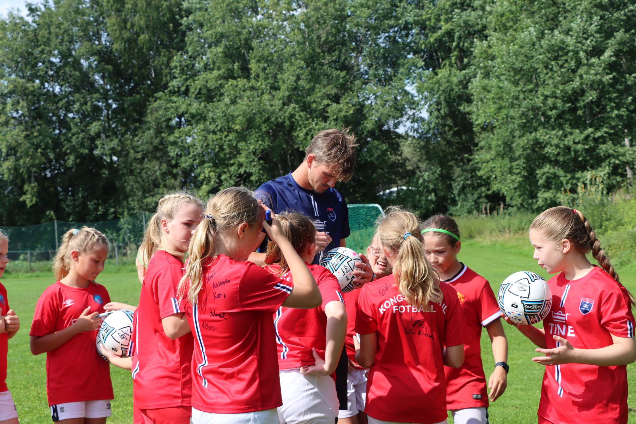De unge fotballspillerene samlet p&aring; signaturer, b&aring;de av hverandre og spillerne fra A-laget.