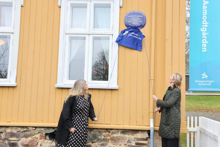 Mona Pedersen (f.v.) i Anno Museum og Aase Eskevik fra Riksantikvaren avduket det blå skiltet som nå pryder Aamodtgården.