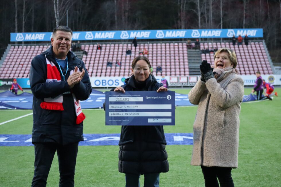 Markedsansvarlig i KIL Toppfotball, Rune Lundgren (t.v.) og Marianne Aspebakken i Kongsvinger Demensforening (midten) er overveldet over støtten som Jannicke S. Mykkestue (t.h.) kunne overrekke på vegne av Gjensidigestiftelsen rett før lørdagens hjemmekamp på Gjemselund.
