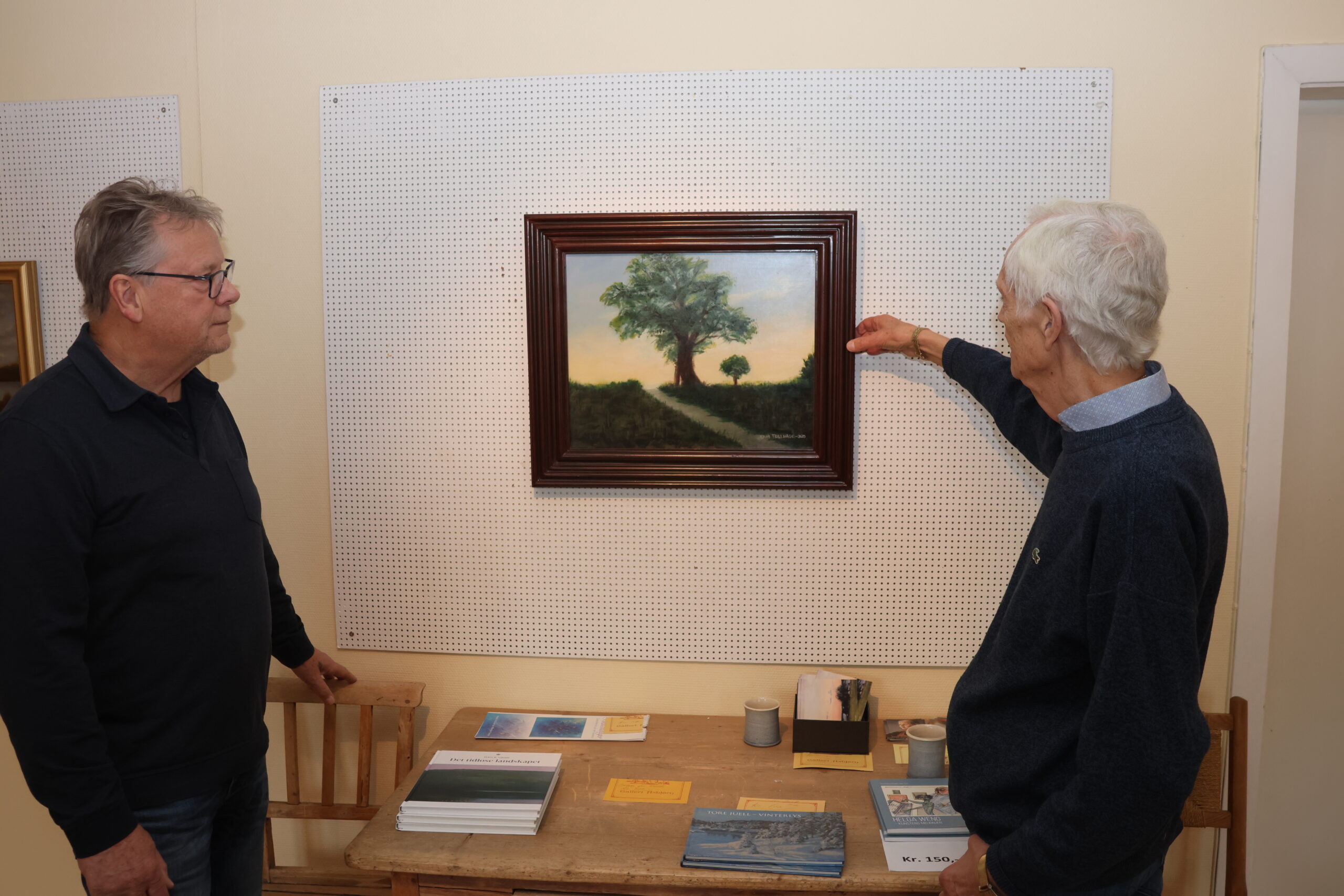 Kunstneren og galleristen diskuterer et av maleriene som skal med i utstillingen.