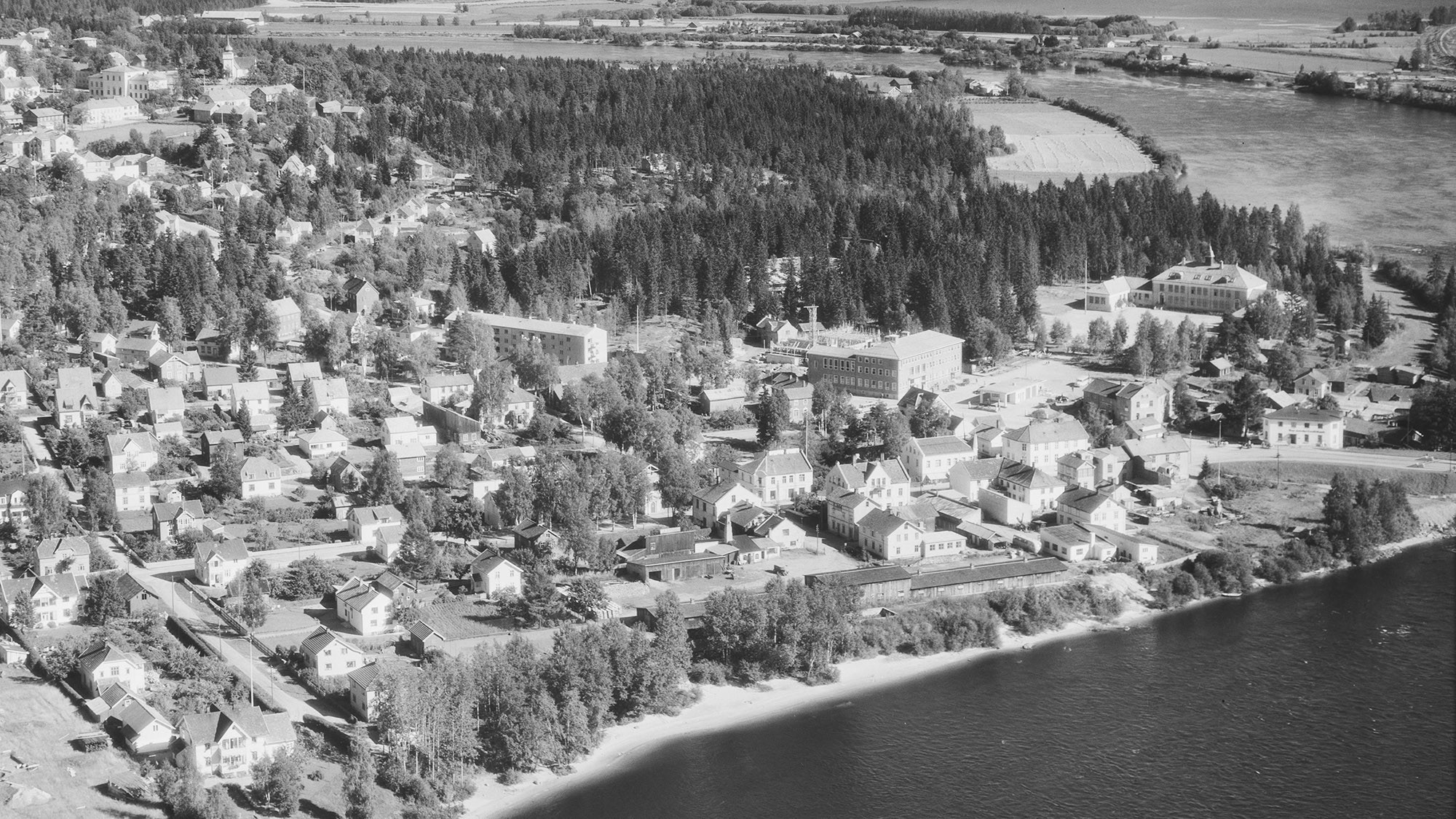 Flyfoto som viser Midtbyen i 1950. KOBBL-bygget står ferdig, mens Rådhusteatret er under oppføring. Hele området bak Folkeskolen er skog og åker.