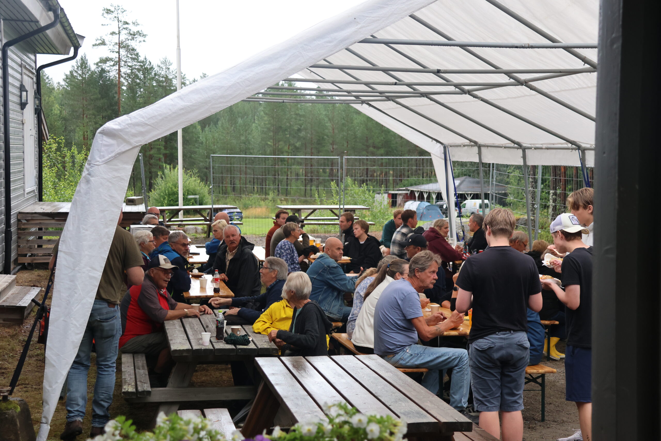 Folk hygget seg med god mat og drikke under presenningen i det ustabile v&aelig;ret.