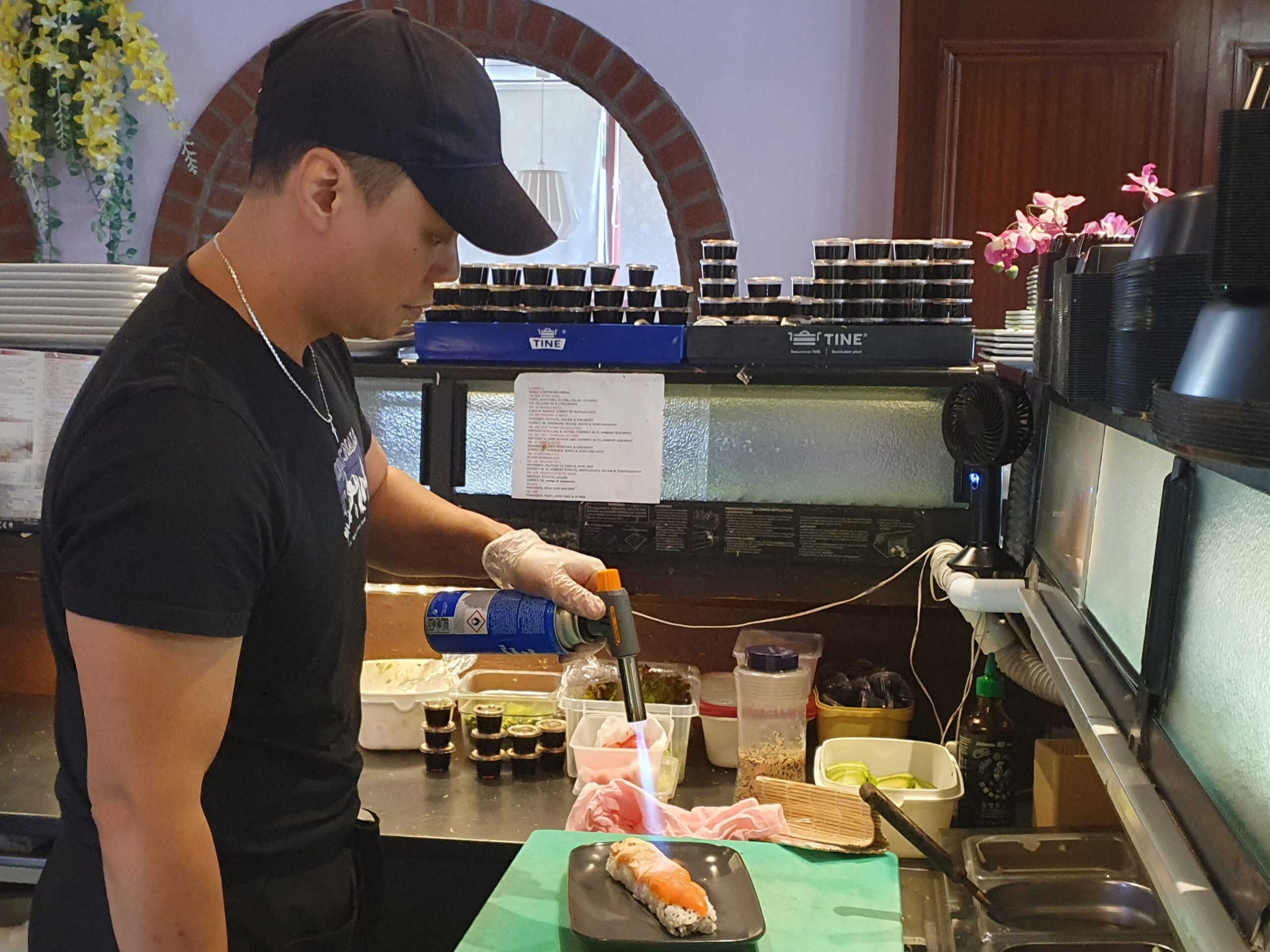 Her flamberer daglig leder Hong Tran en sushi-rett.