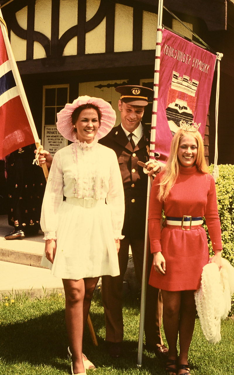 Harry Hansen fra Kongsvinger Bymusikk holder flagg og fane høyt sammen med to lokale representanter fra USA.