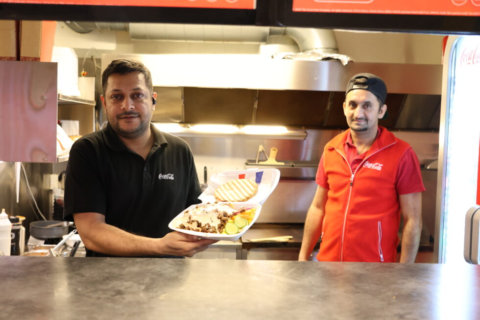 Imran Ahmed, daglig leder hos Charlies Kebab og ansatt Yasir Shinwari viser fram den populære kebabtallerkenen som topper Wolt-statistikken i Kongsvinger i 2025.