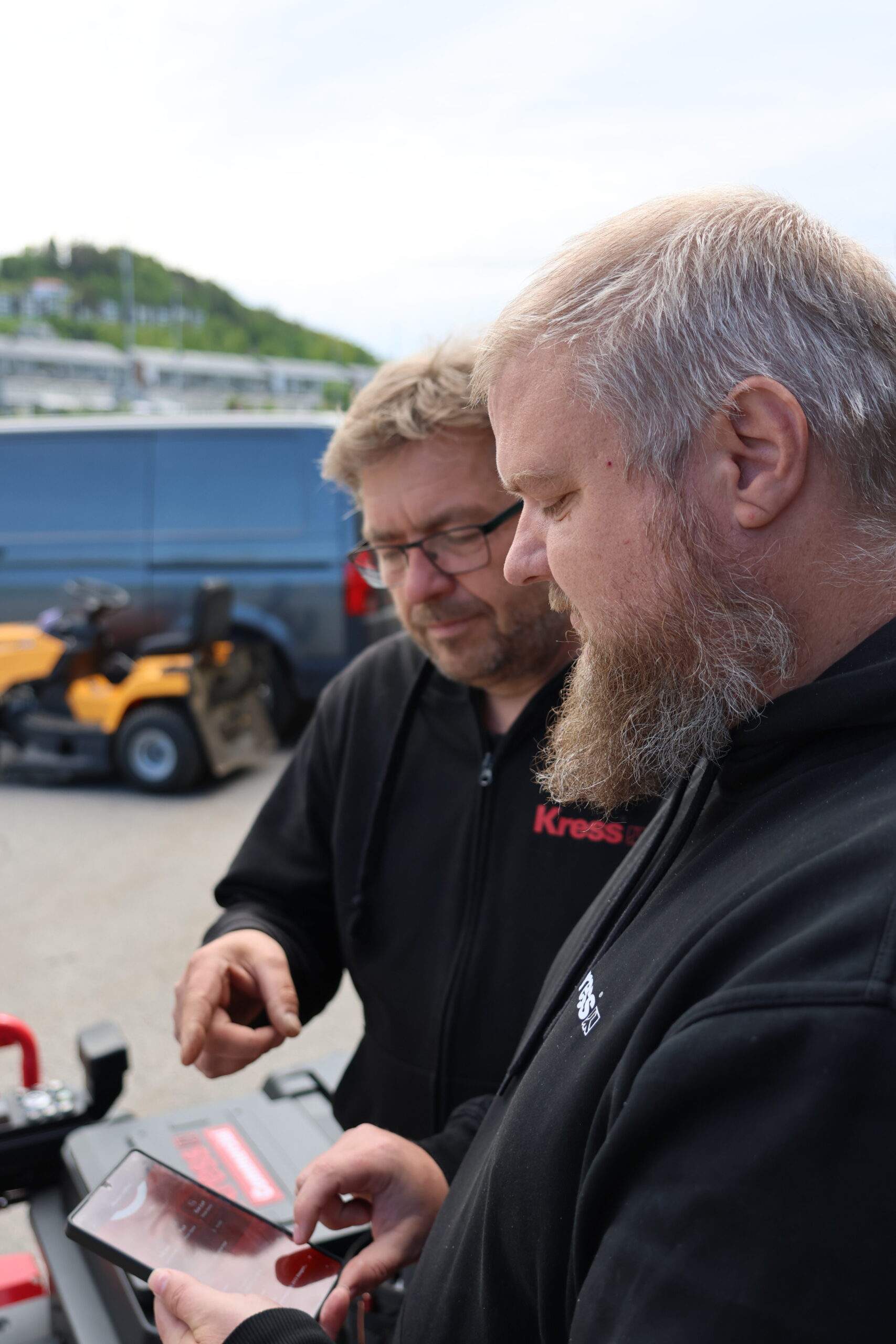 Lars Ove Klokkerengen fra Kress Norge og Kent Magnusson fra Spare AS studerer appen som alt kan styres fra på den nye robotgressklipperen.