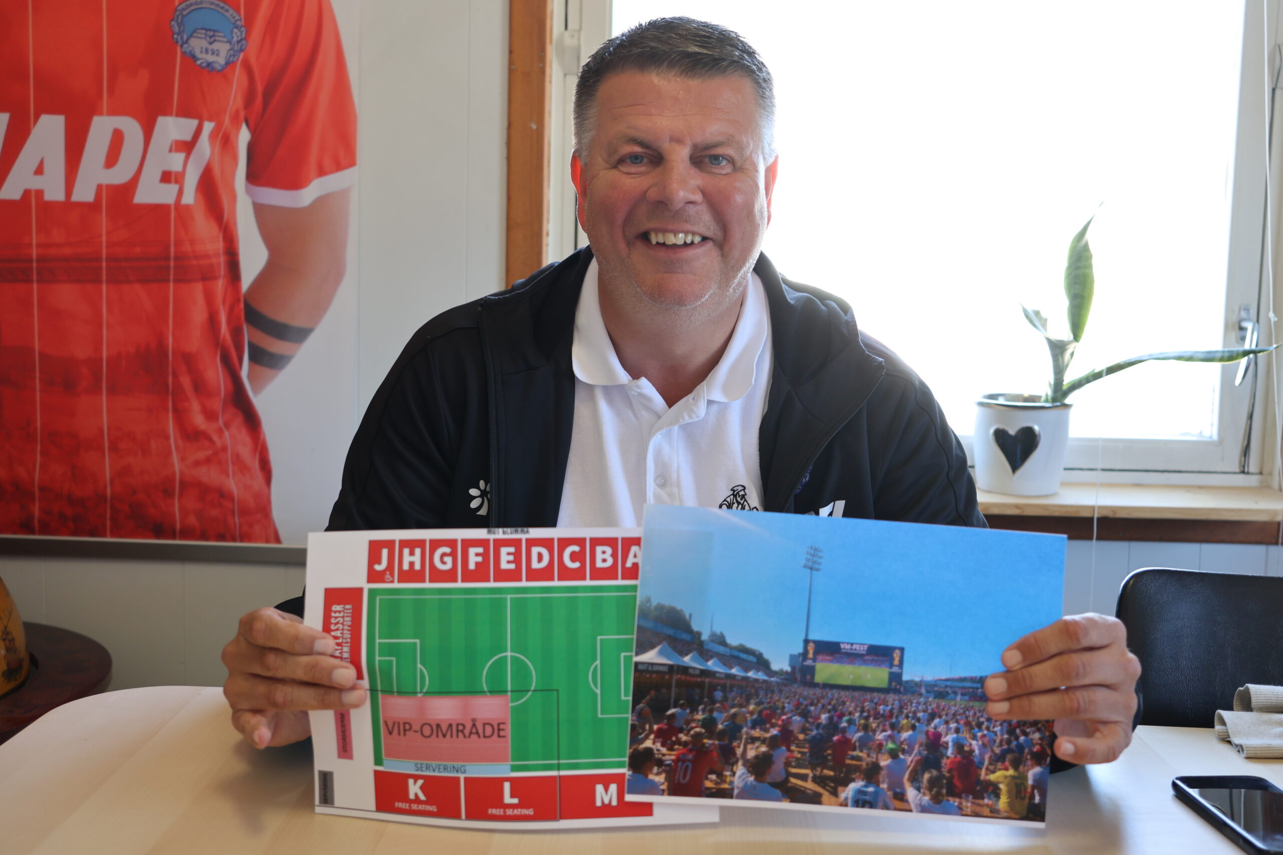 Rune Lundgren viser frem hvordan det kan bli seende ut på Gjemselund under Fotball-VM. På tegningen til venstre kan man se at K og L tribunen vil tas i bruk, samt at det etableres et VIP-område på matta foran storskjermen.