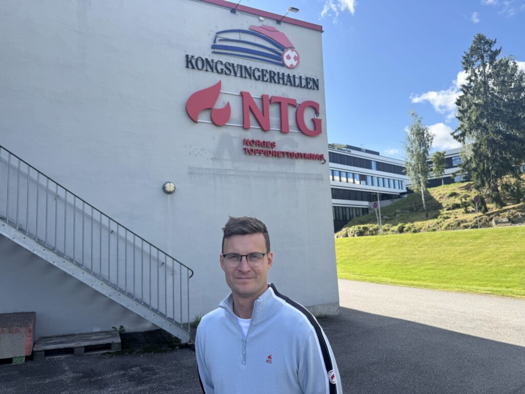 Mann står foran storhallen i Kongsvinger. På skiltet bak står det blant annet NTG.